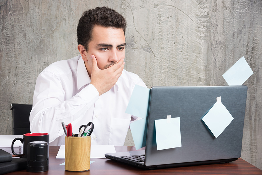 Businessman looking at laptop while holding his mouth at the office desk. High quality photo